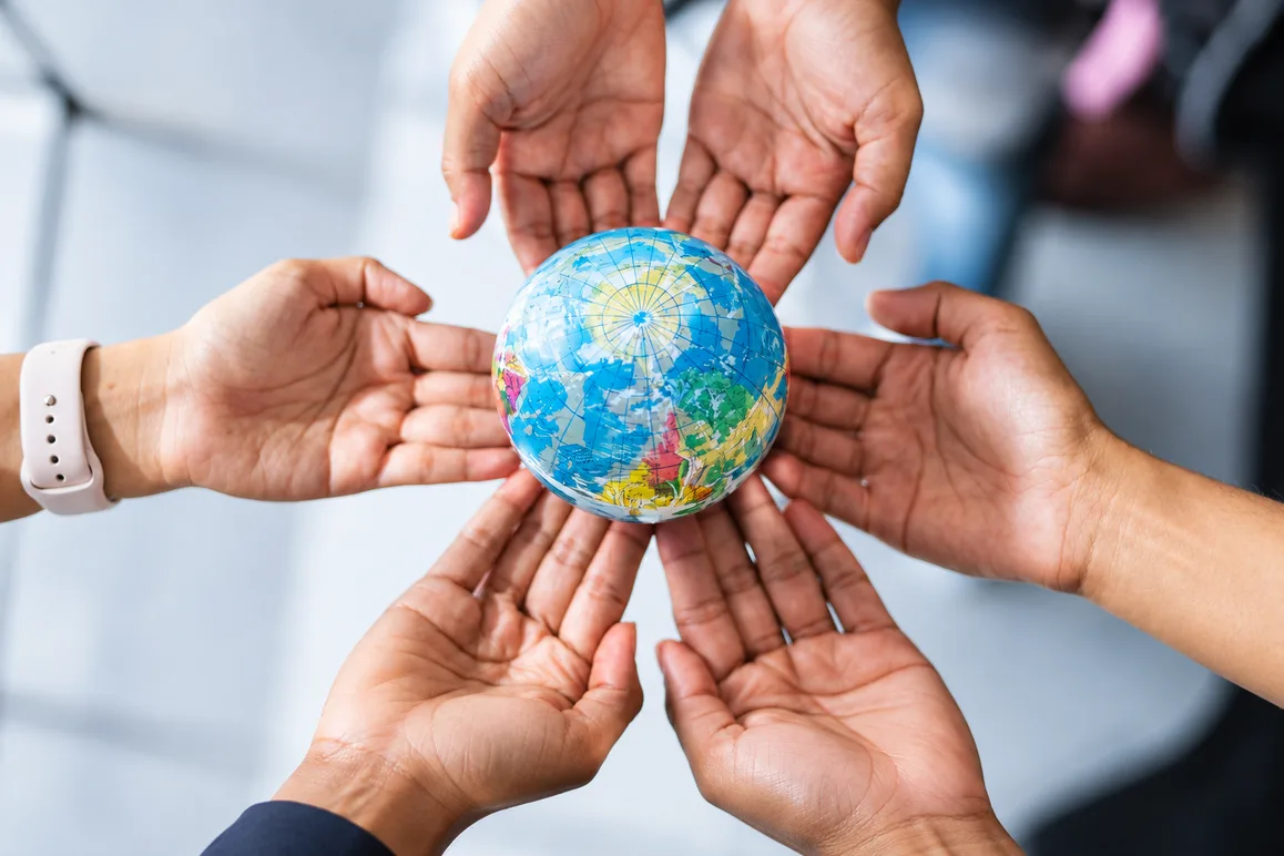 Várias mãos de pessoas diferentes sustentando juntas um globo terrestre