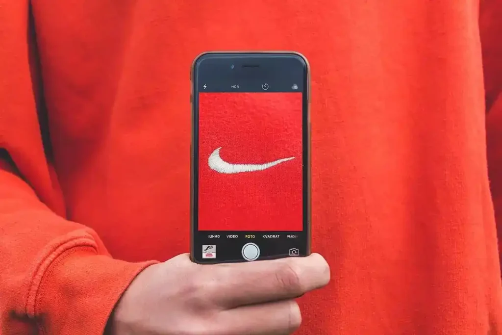 Pessoa segurando celular com câmera focada no logo da Nike, representando a percepção de uma proposta de valor forte para a marca