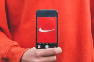 Pessoa segurando celular com câmera focada no logo da Nike, representando a percepção de uma proposta de valor forte para a marca