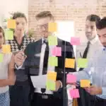 Equipe discutindo estratégias de gestão de mudanças com post-its coloridos.