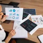 Profissional analisando gráficos impressos sobre indicadores financeiros estratégicos.