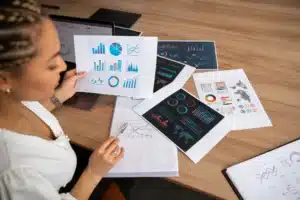 Profissional analisando gráficos impressos sobre indicadores financeiros estratégicos.