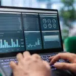 Pessoa utilizando notebook com dashboards inteligentes na tela para análise de dados.