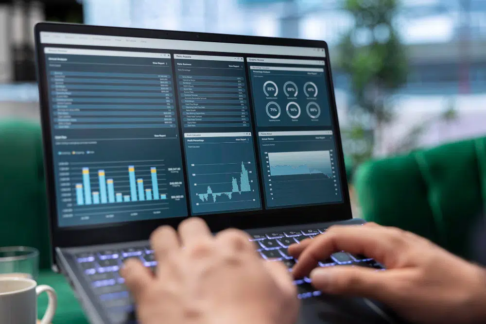 Pessoa utilizando notebook com dashboards inteligentes na tela para análise de dados.