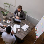 Equipe de consultoria em planejamento estratégico discutindo ideias durante reunião de trabalho com anotações e gráficos em uma mesa de escritório.