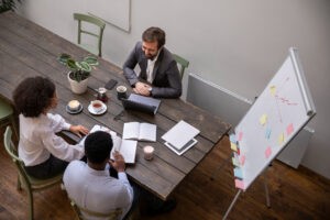 Equipe de consultoria em planejamento estratégico discutindo ideias durante reunião de trabalho com anotações e gráficos em uma mesa de escritório.
